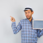 young-man-holding-blank-frame-pointing-away-checked-shirt_176474-24142